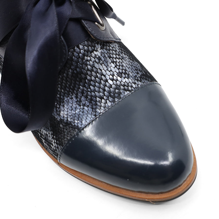 FRONT VIEW OF NAVY LEATHER PATENT FLAT SHOE WITH NAVY RIBBON LACES. 