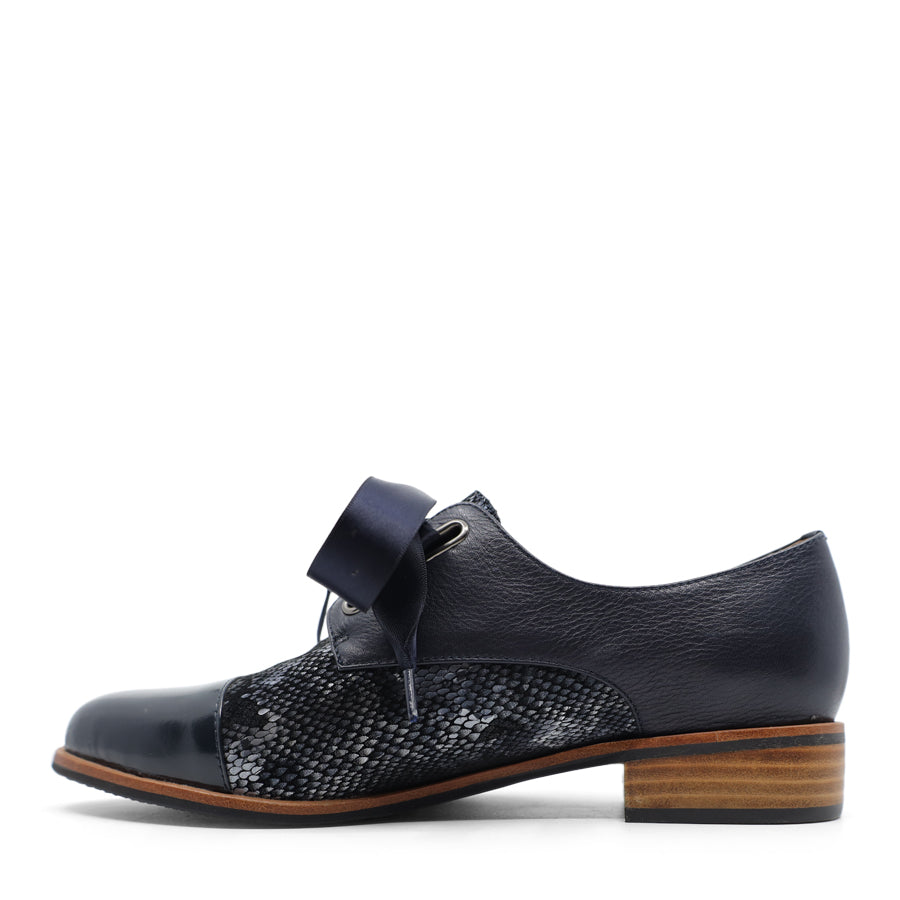 SIDE VIEW OF NAVY LEATHER PATENT FLAT SHOE WITH NAVY RIBBON LACES. 