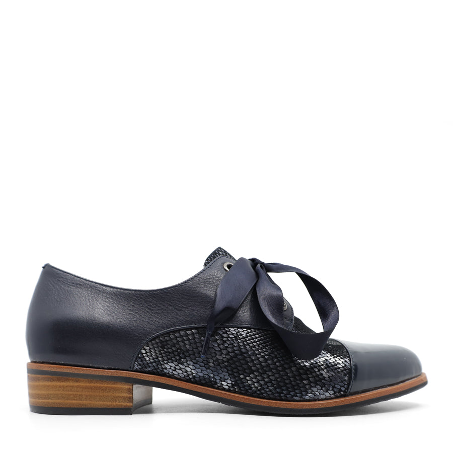 SIDE VIEW OF NAVY LEATHER PATENT FLAT SHOE WITH NAVY RIBBON LACES. 